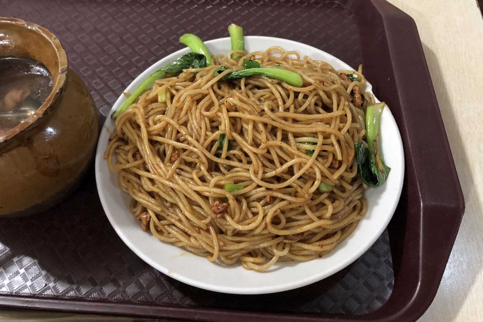 A plate of Nanchang chaofen — glossy wok-fried round rice noodles with greens — beside a clay pot of soup on a tray