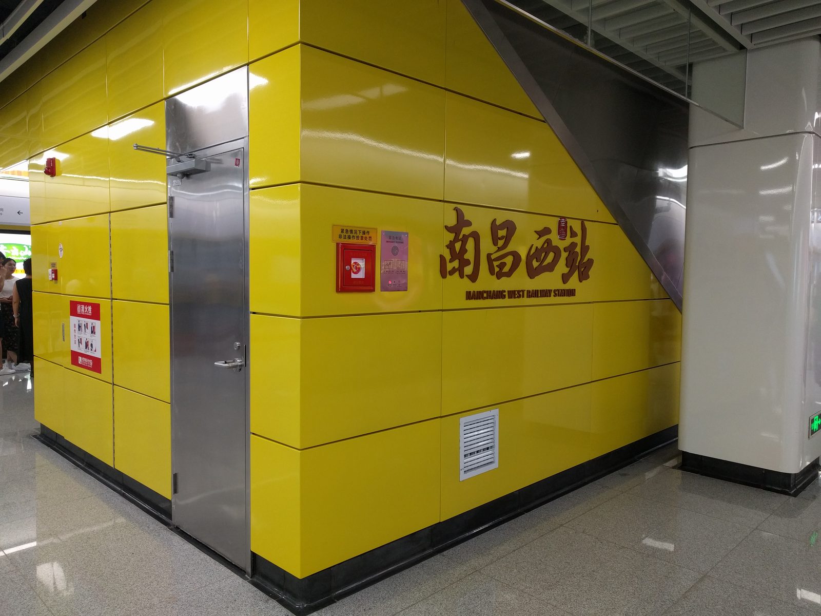 Signage reading 南昌西站 / Nanchang West Railway Station on a yellow-tiled concourse wall