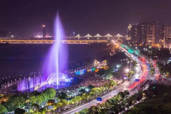 The musical fountain at Qiushui Square on the west bank of the Gan River, Nanchang, shooting a tall lit jet of water into the night above a crowd