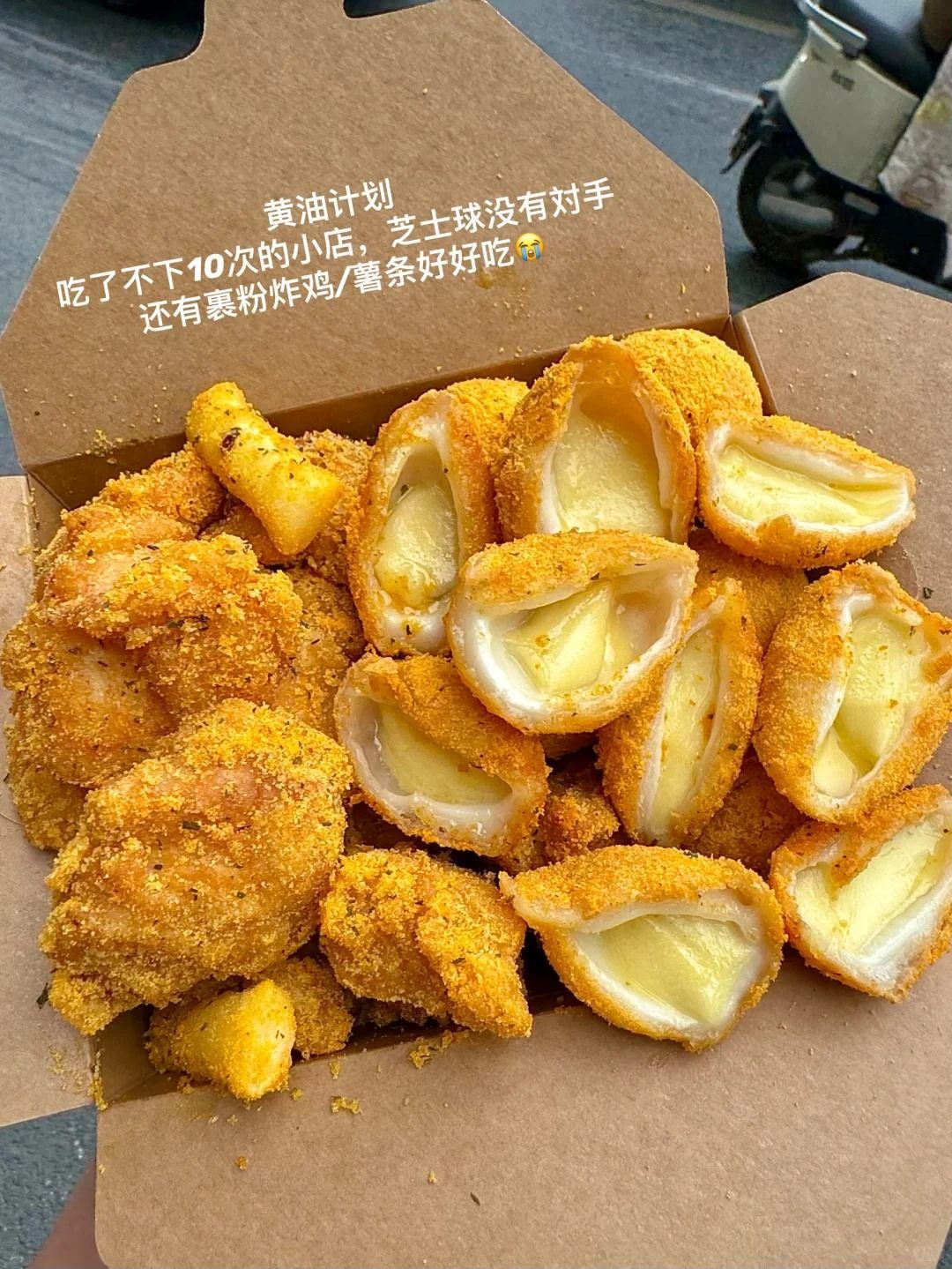 A takeaway box of fried cheese balls and battered fried chicken dusted with seasoning at a Nanchang street stall