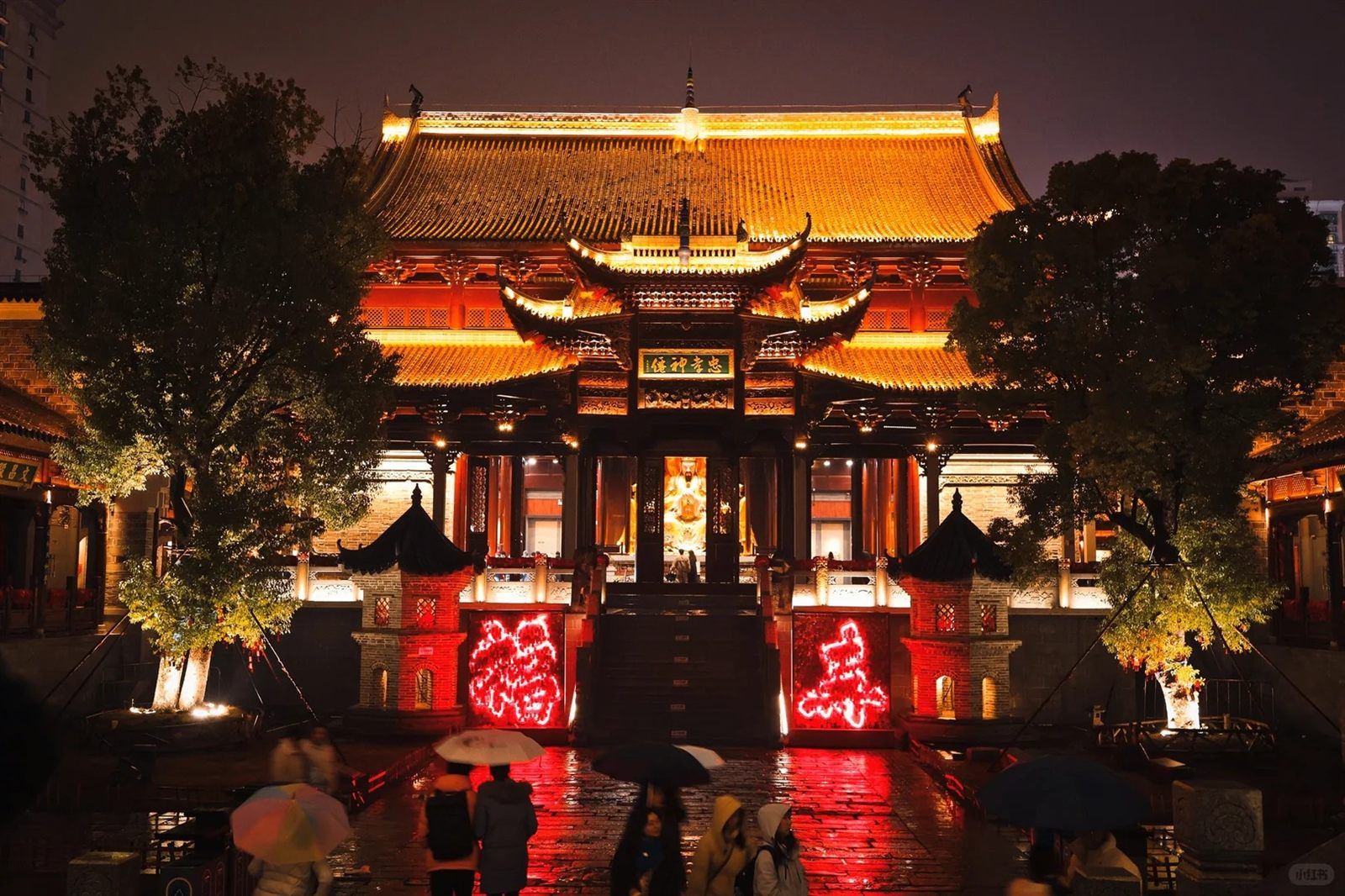 The Iron-Pillar Wanshou Palace temple hall floodlit at night, its carved timber facade and glowing name-plaque above a broad stone staircase